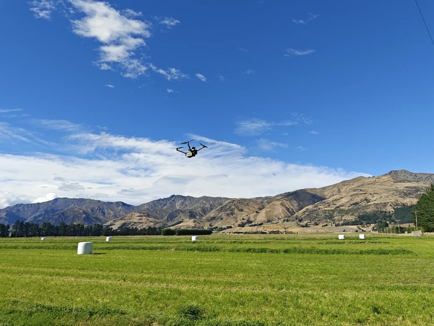A drone flying over pasture beneath the mountains near Hāwea